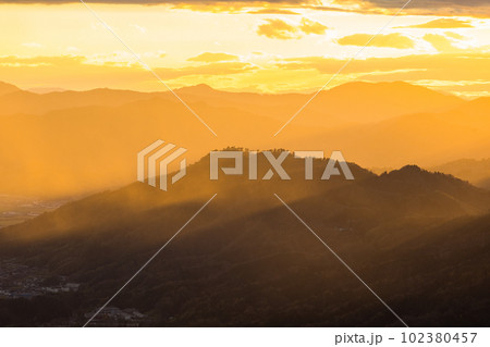 日本 京都府宮津市にある成相山パノラマ展望台から夕焼け空と山々を照らす光芒 日本 京都府宮津市にある成相山パノラマ展望台から夕焼け空と山々を照らす光芒 102380457