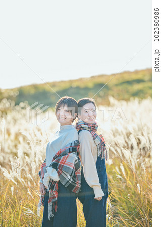 ススキを背景に背中合わせに立つ若い女性と友達 102380986