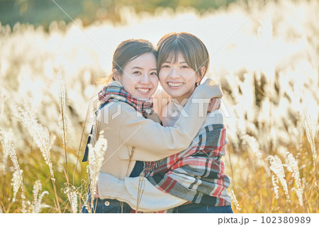 ススキを背景に抱き合う若い女性と友達 102380989