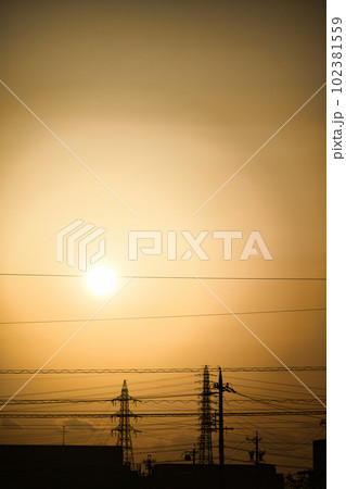 夕焼けで黄色く霞む空と建物のシルエット 102381559