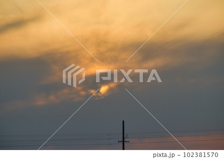 夕焼けで黄色く霞む空と建物のシルエット 102381570