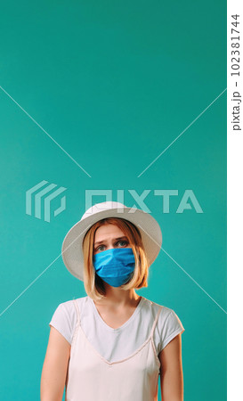 Pandemic hygiene. Grippe prevention. Upset dissatisfied woman in white and medical mask flu epidemic isolated on turquoise copy space background. Pandemic hygiene. Grippe prevention. Upset dissatisfied woman in white and medical mask flu epidemic isolated on turquoise copy space background. 102381744