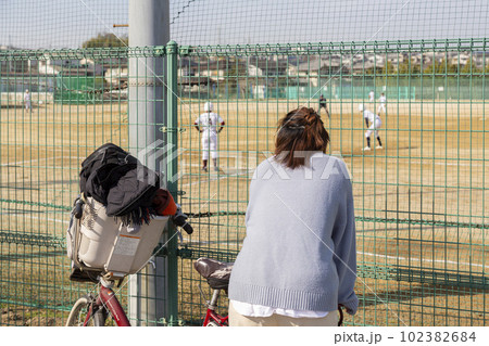 フェンス越しに少年野球を観戦する女性(母親) フェンス越しに少年野球を観戦する女性(母親) 102382684