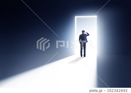 Businessman entering backlit door in escape concept Businessman entering backlit door in escape concept 102382692