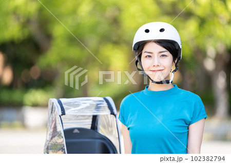 ヘルメットを被って自転車に乗る女性。 102382794