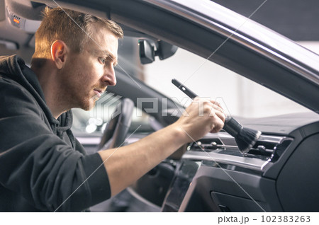 Professional detailing a car in the studio, hands with brush cleaning car interior from a dust, vehicle care concept 102383263
