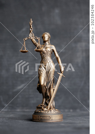 themis is goddess of justice statuette on dark background. symbol of law with scales  102384246
