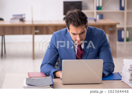 Young male employee and too much work in the office Young male employee and too much work in the office 102384448