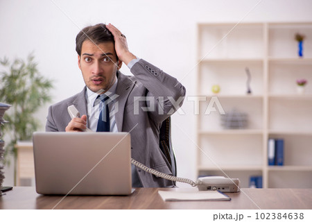 Young male employee and too much work in the office Young male employee and too much work in the office 102384638