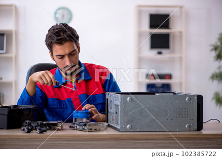 Young male repairman repairing computer Young male repairman repairing computer 102385722