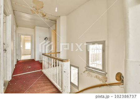 the inside of an old house with red carpet and peeling paint on the walls there is a staircase leading up to the second floor 102386737