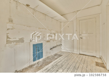 an old room with wood floors and peeling paint on the walls, including a blue door in the middle part of the room an old room with wood floors and peeling paint on the walls, including a blue door in the middle part of the room 102386738