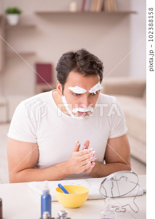 Young man shaving face at home 102388158