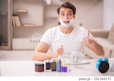Young man shaving face at home Young man shaving face at home 102388175
