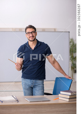 Young male teacher sitting in the classroom 102388287