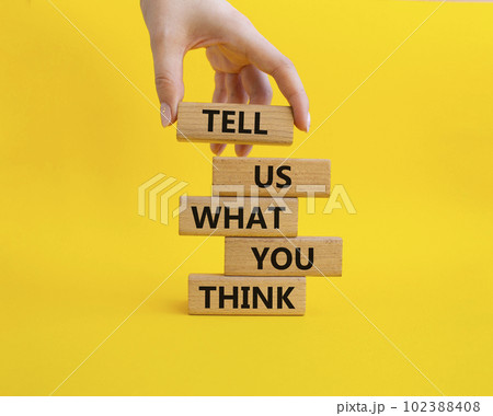 Tell us what you think symbol. Wooden blocks with words Tell us what you think. Beautiful yellow background. Businessman hand. Business and Tell us what you think concept. Copy space. 102388408