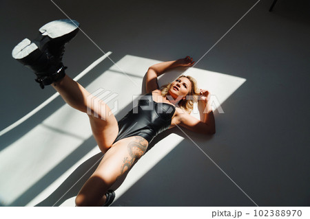 a bold and sexy blonde in a leather swimsuit and boots on the white floor a bold and sexy blonde in a leather swimsuit and boots on the white floor 102388970