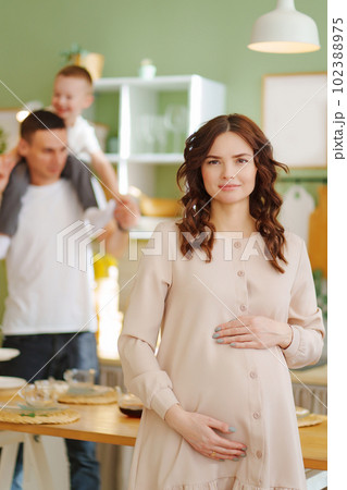 pregnant mom against the background of son and dad In the kitchen. 102388975