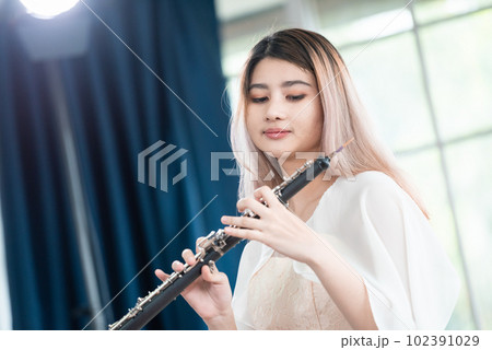 Portrait of Young Female Musician Playing Clarinet. Rehearsal before performing on stage. 102391029