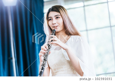 Portrait of Young Female Musician Playing Clarinet. Rehearsal before performing on stage. 102391031