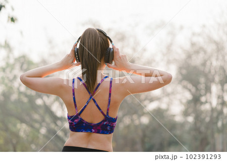 A relaxed woman is shown enjoying music while jogging through a public park. The young lady is feeling free, relaxed, and happy. A relaxed woman is shown enjoying music while jogging through a public park. The young lady is feeling free, relaxed, and happy. 102391293