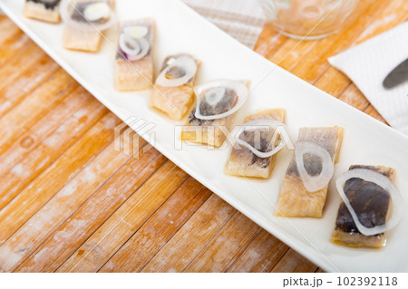 Salted pickled herring fish served on a ceramic plate 102392118