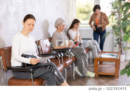 Woman is sitting in the lobby of a large company, waiting for her turn to see specialist in office Woman is sitting in the lobby of a large company, waiting for her turn to see specialist in office 102392435