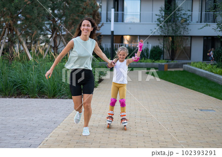 Mother helps daughter learn to roller skate. Mother helps daughter learn to roller skate. 102393291