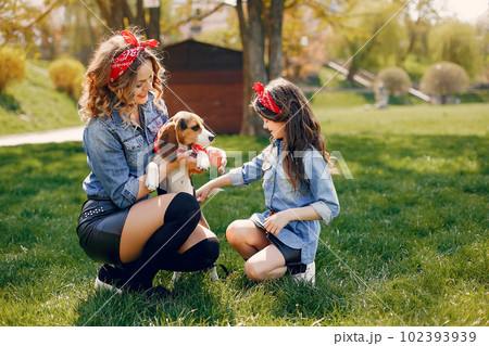 Beautiful mother with daughter. Family in a spring park. Woman in a blue shirt. Family with a cute dog 102393939