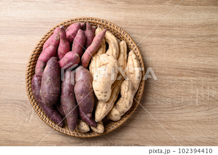 Organic Asian sweet potatoes in basket on wooden background, Table top view Organic Asian sweet potatoes in basket on wooden background, Table top view 102394410