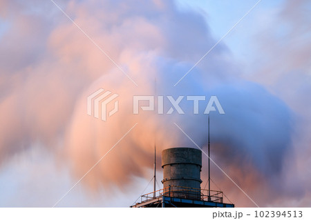 夕日に染まる煙突から吹き上がる白煙 102394513