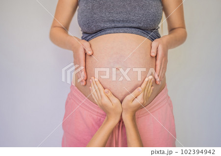 Young beautiful pregnant woman and eldest son. The cute boy put his hands on his mother's belly. Expecting a baby in the family concept. Preparing an older child for a younger one Young beautiful pregnant woman and eldest son. The cute boy put his hands on his mother's belly. Expecting a baby in the family concept. Preparing an older child for a younger one 102394942