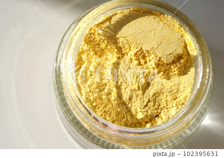 An open jar of a yellow turmeric facial scrub showing off its texture. An open jar of a yellow turmeric facial scrub showing off its texture. 102395631