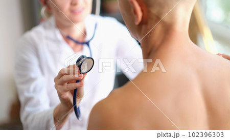Female doctor listening heart or lungs of man patient with stethoscope Female doctor listening heart or lungs of man patient with stethoscope 102396303