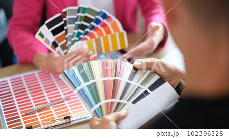Woman designer holding fan of colourful paper samples in hand. 102396328