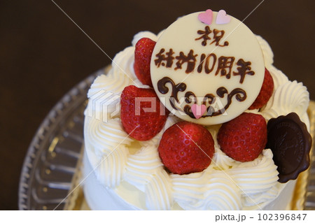 結婚記念日のお祝メッセージが書かれた生クリームのホールケーキ(アップで撮影) 結婚記念日のお祝メッセージが書かれた生クリームのホールケーキ(アップで撮影) 102396847