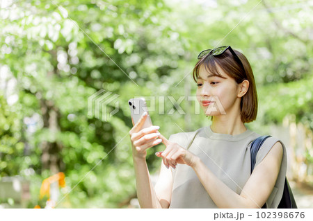 新緑の中スマートフォンを使う女子大生 新緑の中スマートフォンを使う女子大生 102398676