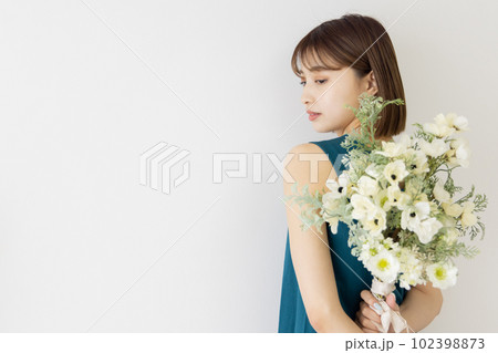 花束を背中で持つ若い女性 102398873