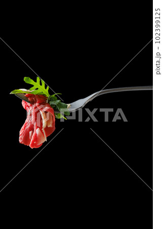 Marbled beef carpaccio on fork over black background 102399125