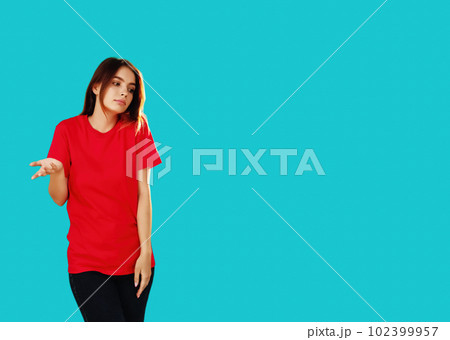 Whatever gesture. Clueless woman. No idea. Overwhelmed girl in red T-shirt doubtful expression shrugging shoulders isolated on cyan blue empty space background. 102399957