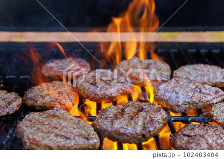 Grilled American beef burger barbecued over hot grill on flames of grill 102403404