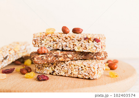 Various granola bars on table background. Cereal granola bars. Superfood breakfast bars with oats, nuts and berries, close up. Superfood concept Various granola bars on table background. Cereal granola bars. Superfood breakfast bars with oats, nuts and berries, close up. Superfood concept 102403574