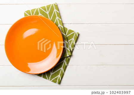 Top view on colored background empty round red plate on tablecloth for food. Empty dish on napkin with space for your design Top view on colored background empty round red plate on tablecloth for food. Empty dish on napkin with space for your design 102403997