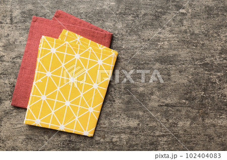 top view with yellow empty kitchen napkin isolated on table background. Folded cloth for mockup with copy space, Flat lay. Minimal style 102404083