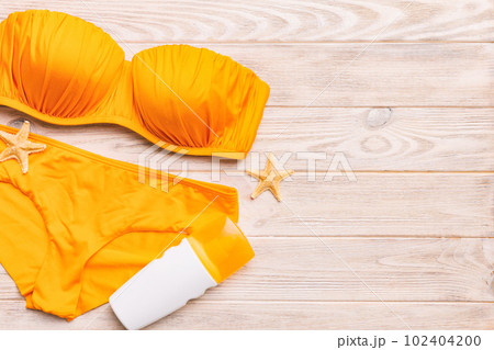 Woman swimwear and beach accessories flat lay top view on colored background Summer travel concept. bikini swimsuit, straw hat and seasheels. Copy space Top view Woman swimwear and beach accessories flat lay top view on colored background Summer travel concept. bikini swimsuit, straw hat and seasheels. Copy space Top view 102404200