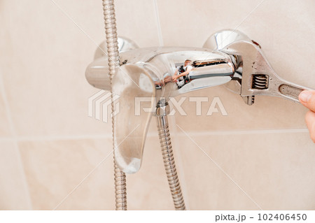 A plumber repairs or installs a faucet faucet in the bathroom A plumber repairs or installs a faucet faucet in the bathroom 102406450