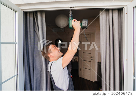 A repairman repairs or adjusts window frames or glass doors on the terrace. A repairman repairs or adjusts window frames or glass doors on the terrace. 102406478