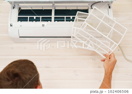 A man replaces and cleans the air cleaner filter from the air conditioner. 102406506