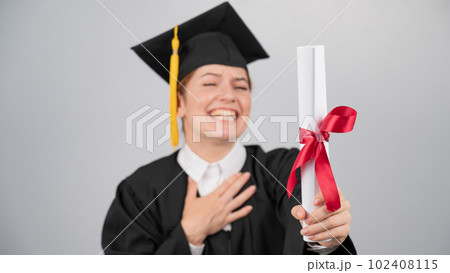 Smiling woman in graduation gown holding diploma on white background.  102408115