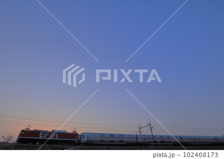 日没の寝台特急カシオペア返却回送　斬首に染まる空をバックに機関車EF8195レインボーが行く 102408173